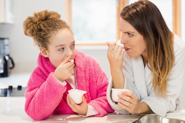 La madre y la hija de comer helado en la cocina