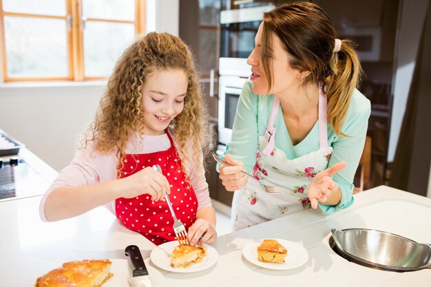 La madre y la hija de comer panqueques en la cocina