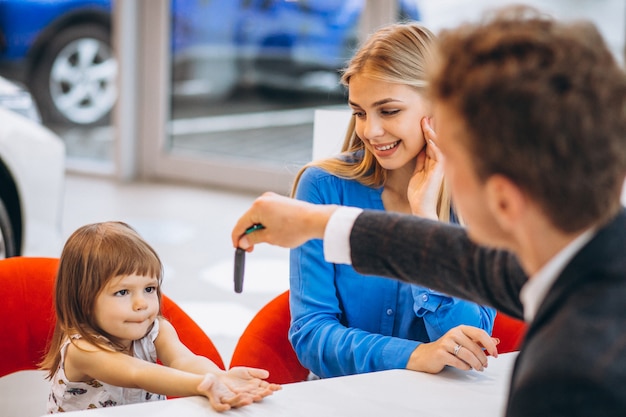 Madre con hija comprando un automóvil en una sala de exposición de automóviles