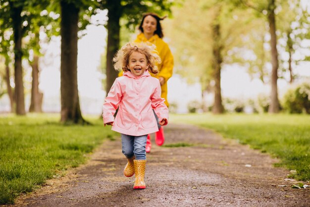 Madre con hija divirtiéndose en el parque en un clima lluvioso