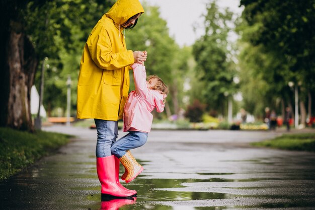 Madre con hija divirtiéndose en el parque en un clima lluvioso