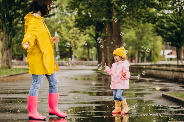 Madre con hija divirtiéndose en el parque en un clima lluvioso