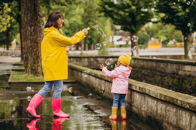 Foto gratuita madre con hija divirtiéndose en el parque en un clima lluvioso