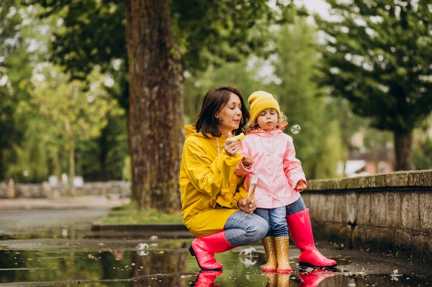 Madre con hija divirtiéndose en el parque en un clima lluvioso