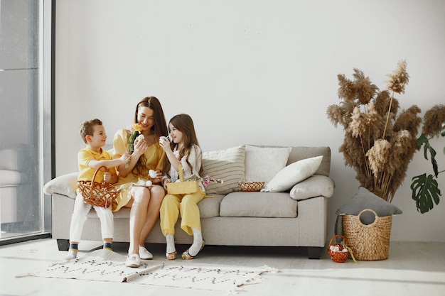 Madre con hija e hijo en casa. Haz una canasta navideña. Con ropa festiva