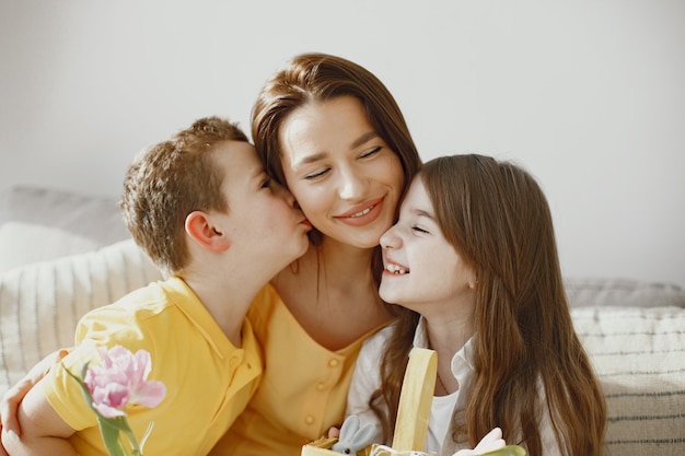 Madre con hija e hijo en casa. Haz una canasta navideña. Con ropa festiva