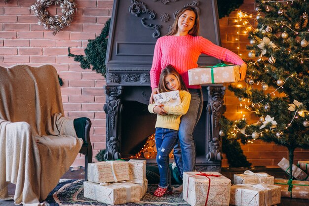 Madre con hija empacando presente por chimenea en navidad