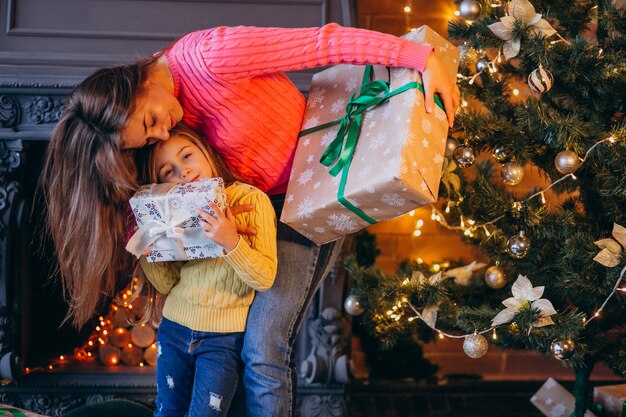 Madre con hija empacando presente por chimenea en navidad