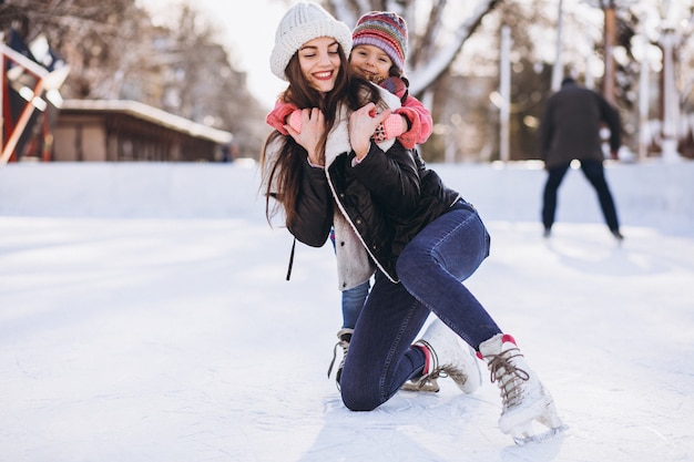 Madre con hija enseñando patinaje sobre hielo en una pista