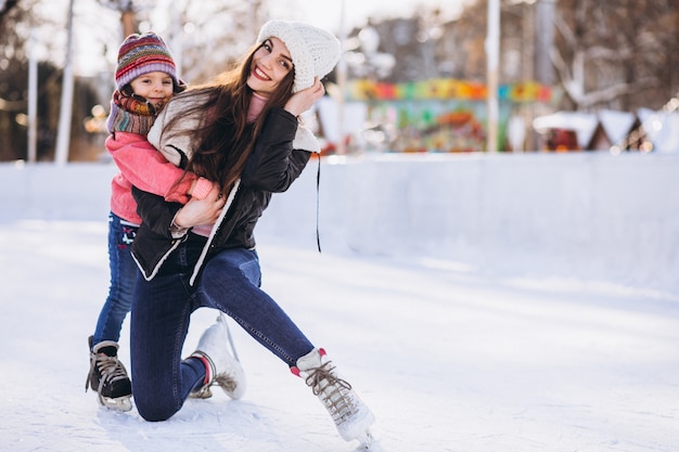 Madre con hija enseñando patinaje sobre hielo en una pista