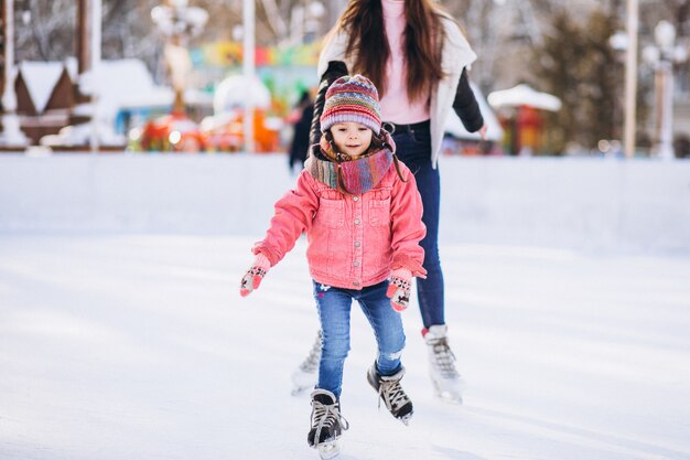 Madre con hija enseñando patinaje sobre hielo en una pista