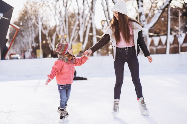 Madre con hija enseñando patinaje sobre hielo en una pista