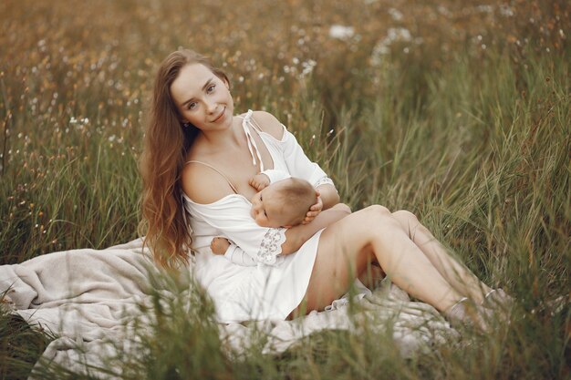 Madre con hija. Familia en un campo. Niña recién nacida. Mujer con un vestido blanco.