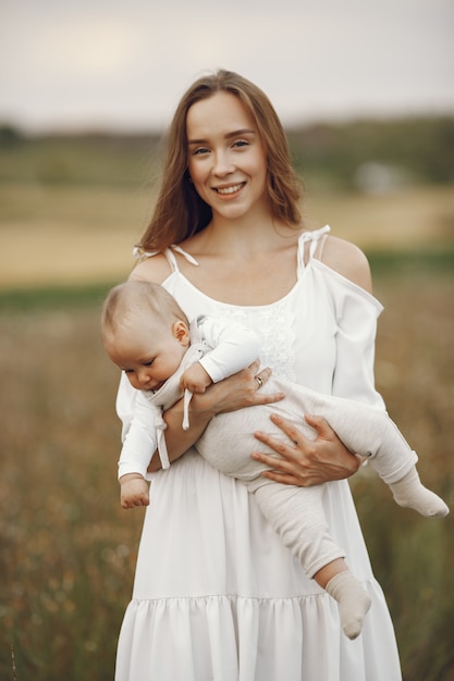 Madre con hija. Familia en un campo. Niña recién nacida. Mujer con un vestido blanco.