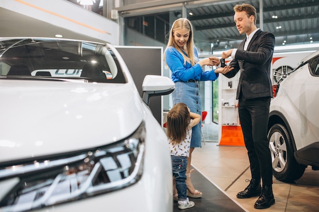 Madre con hija hablando con vendedor en una sala de exposición de automóviles