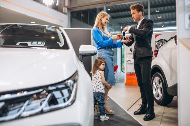 Madre con hija hablando con vendedor en una sala de exposición de automóviles