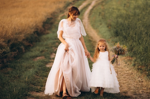Madre con hija en hermosos vestidos en el campo