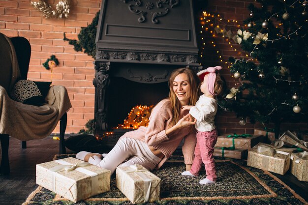 Madre con hija junto a la chimenea en navidad