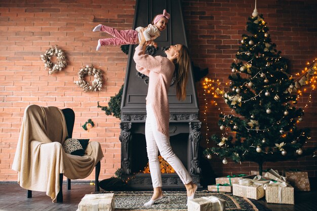 Madre con hija junto a la chimenea en navidad