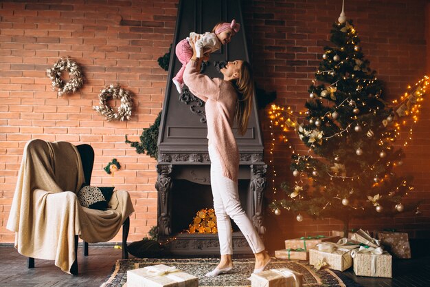 Madre con hija junto a la chimenea en navidad