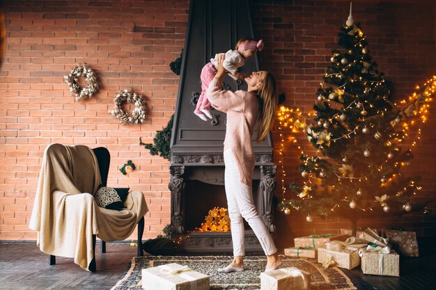 Madre con hija junto a la chimenea en navidad