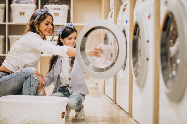 Foto gratuita madre con hija lavando ropa en la lavandería de autoservicio