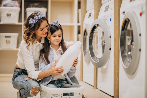 Madre con hija lavando ropa en la lavandería de autoservicio