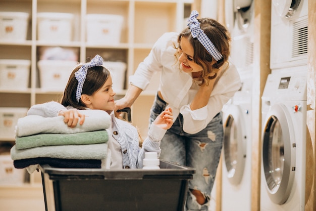 Foto gratuita madre con hija lavando ropa en la lavandería de autoservicio