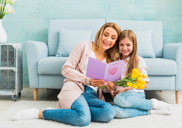 Madre con hija leyendo la postal del día de la madre.