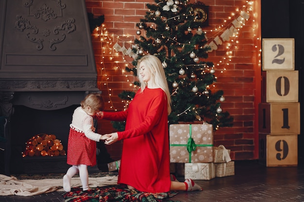 Madre con hija linda en casa en un vestido rojo