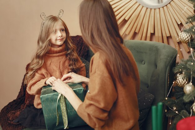 Madre con hija linda cerca del árbol de navidad