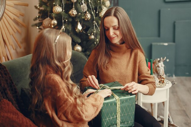 Madre con hija linda cerca del árbol de navidad