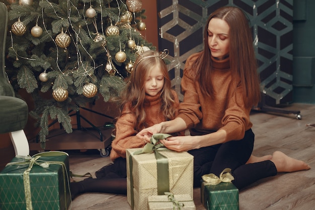 Madre con hija linda cerca del árbol de navidad