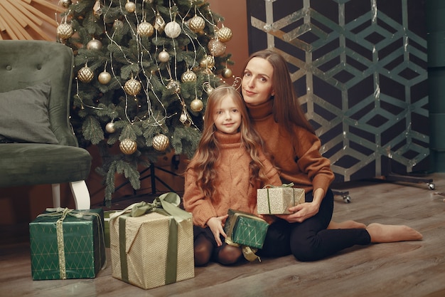 Madre con hija linda cerca del árbol de navidad