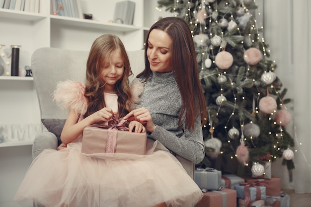 Madre con hija linda cerca del árbol de navidad