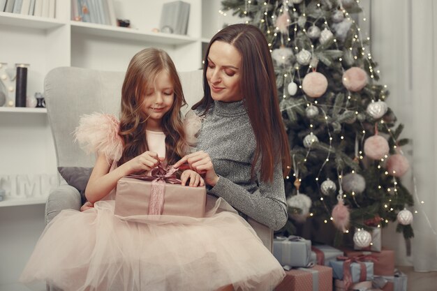 Madre con hija linda cerca del árbol de navidad