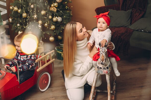 Madre con hija linda cerca del árbol de navidad