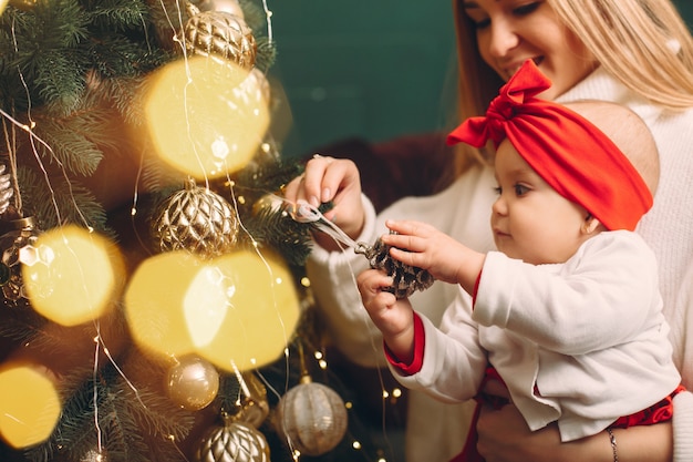 Madre con hija linda cerca del árbol de navidad