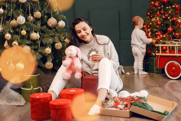 Madre con hija linda cerca del árbol de navidad