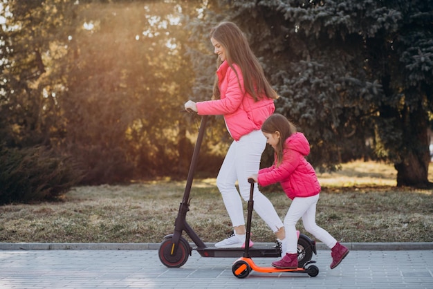 Madre con hija montando scooter eléctrico