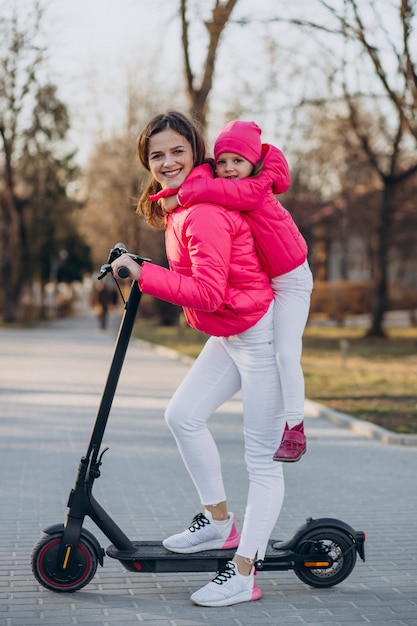 Madre con hija montando scooter eléctrico