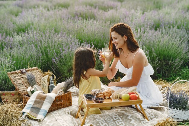 Madre con hija pequeña en campo de lavanda. Mujer hermosa y lindo bebé jugando en el campo del prado. Familia en un picnic.