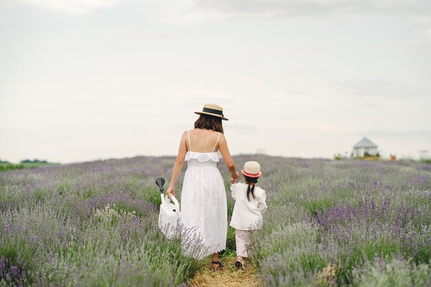 Madre con hija pequeña en campo de lavanda. Mujer hermosa y lindo bebé jugando en el campo del prado. Vacaciones familiares en verano.