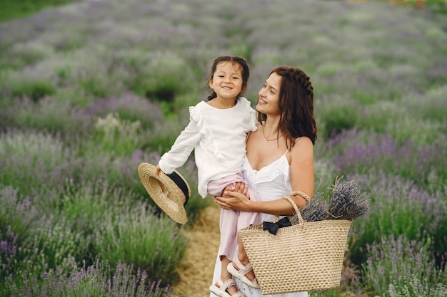 Madre con hija pequeña en campo de lavanda. Mujer hermosa y lindo bebé jugando en el campo del prado. Vacaciones familiares en verano.