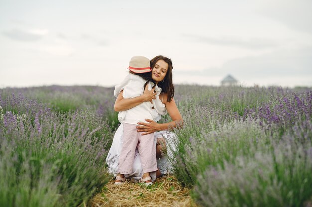 Madre con hija pequeña en campo de lavanda. Mujer hermosa y lindo bebé jugando en el campo del prado. Vacaciones familiares en verano.