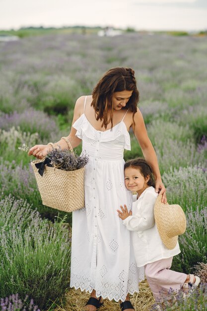 Madre con hija pequeña en campo de lavanda. Mujer hermosa y lindo bebé jugando en el campo del prado. Vacaciones familiares en verano.