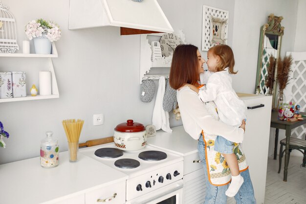 Madre con hija pequeña cocinando en casa