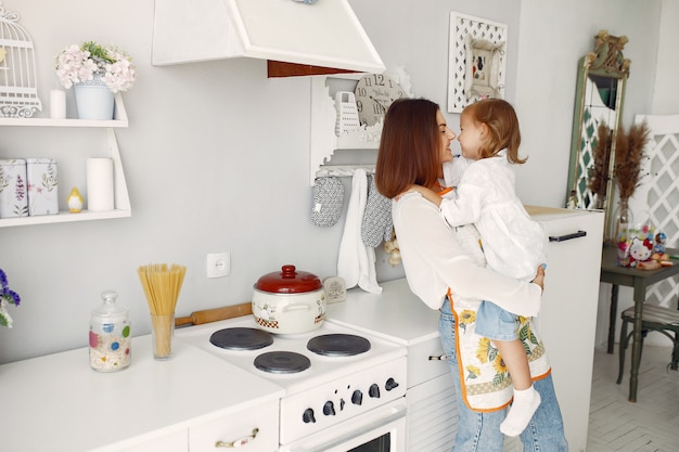 Madre con hija pequeña cocinando en casa