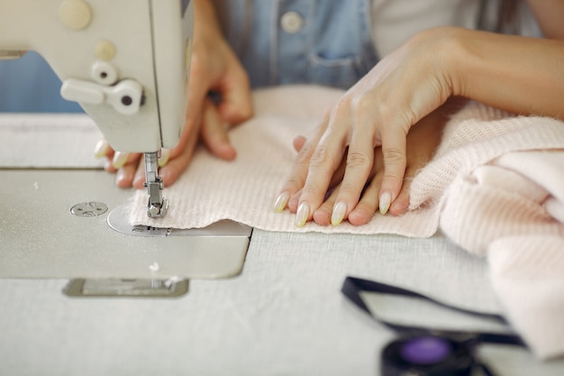 Madre con hija pequeña coser ropa en la fábrica