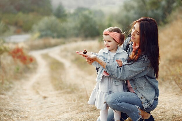 Madre con hija pequeña jugando en un campo con una mariposa